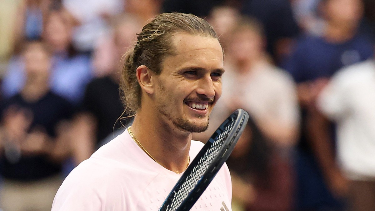 Alexander Zverev of Germany smiles with his racket raised beside his face after a match.