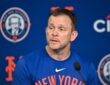 New York Mets manager Andrew Green speaks into a microphone during a press conference in front of a Mets backdrop.