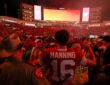 Texas quarterback Arch Manning stands with his back to the camera in his No. 16 jersey as fans flood the field around him.