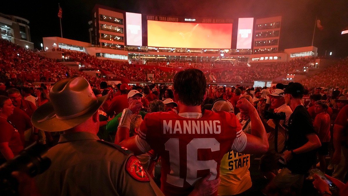 Texas quarterback Arch Manning stands with his back to the camera in his No. 16 jersey as fans flood the field around him.