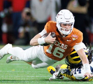 Texas Longhorns quarterback Arch Manning stretches the ball forward as Michigan's Jordan Young tackles him.