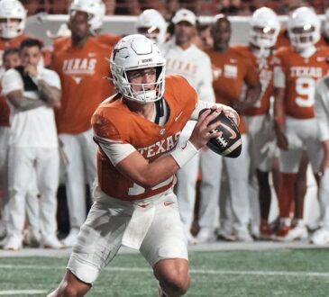 Texas Longhorns quarterback Arch Manning rolls out with the ball in both hands as a UTSA defender closes in.