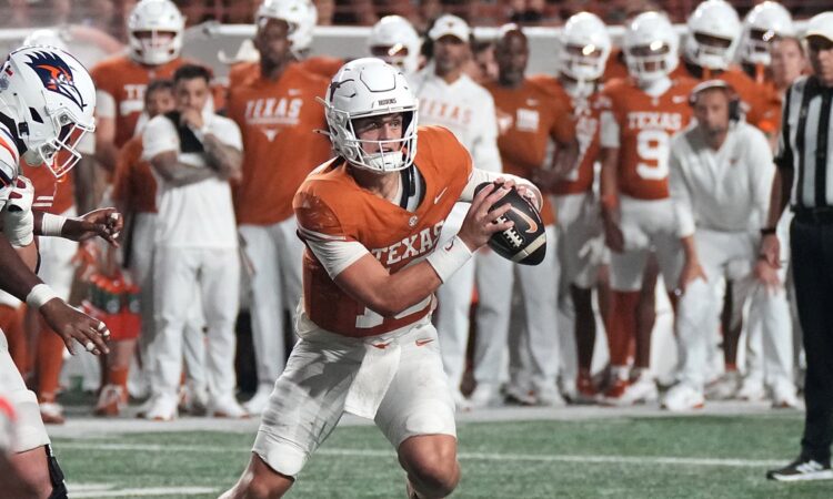 Texas Longhorns quarterback Arch Manning rolls out with the ball in both hands as a UTSA defender closes in.