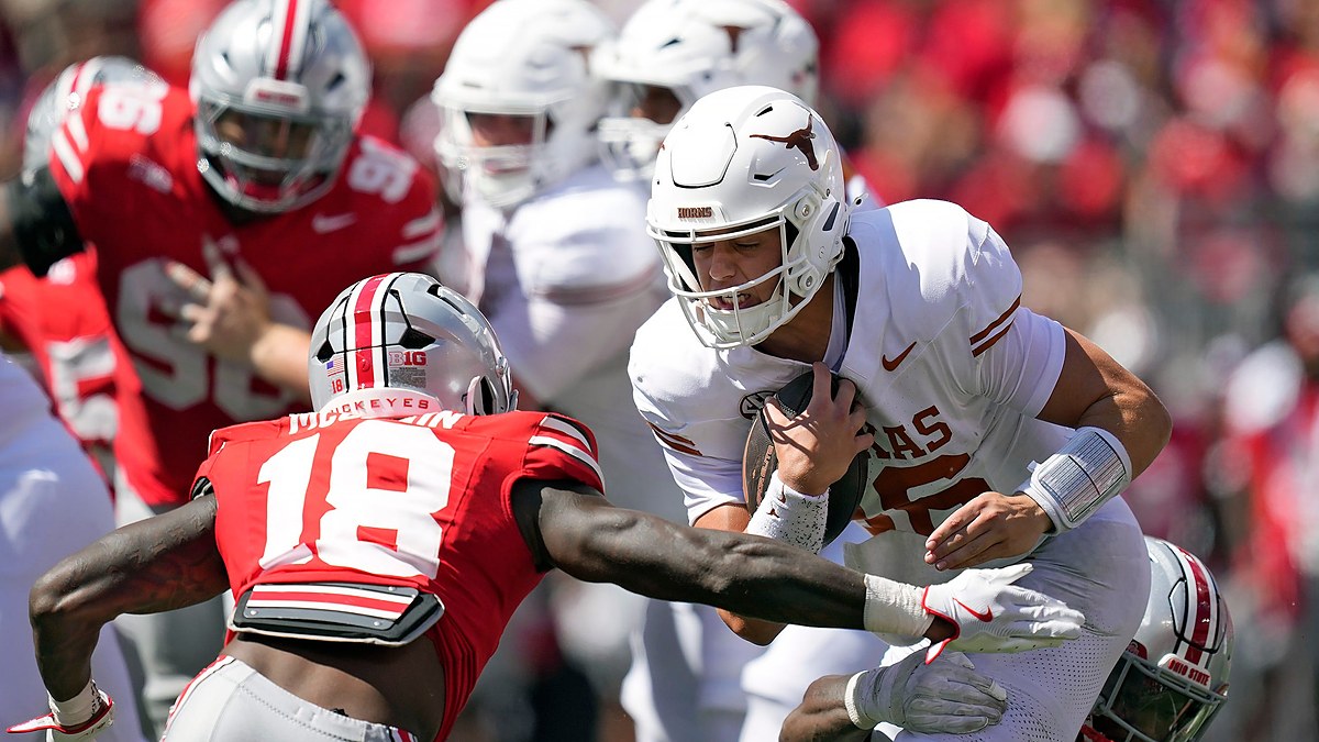 Ohio State Buckeyes safety Jaylen McClain reaches to tackle Texas quarterback Arch Manning as he runs with the ball.