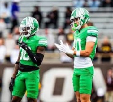 North Texas Mean Green wide receiver Baron Tipton, No. 80, stands on the field beside a teammate during a road game.