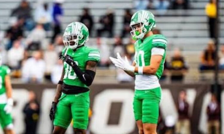 North Texas Mean Green wide receiver Baron Tipton, No. 80, stands on the field beside a teammate during a road game.