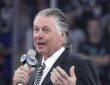 Former Los Angeles Kings coach Barry Melrose speaks into a microphone during a pregame ceremony.