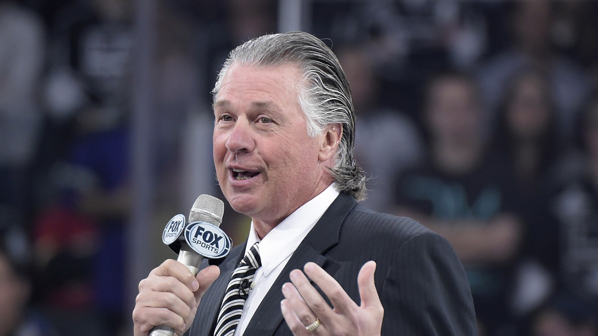 Former Los Angeles Kings coach Barry Melrose speaks into a microphone during a pregame ceremony.