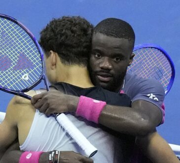 Ben Shelton, back to camera, and Frances Tiafoe hug at the net with their rackets raised after a match.
