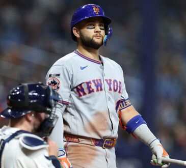 New York Mets third baseman Bo Bichette stands at the plate holding his bat as the Tampa Bay Rays catcher looks away.