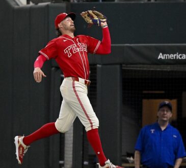 Texas Rangers right fielder Brandon Nimmo reaches up with his glove to catch a foul ball on the run.