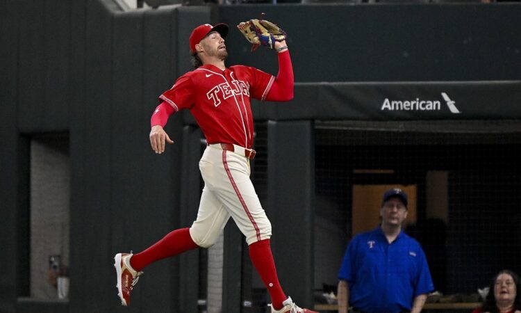 Texas Rangers right fielder Brandon Nimmo reaches up with his glove to catch a foul ball on the run.