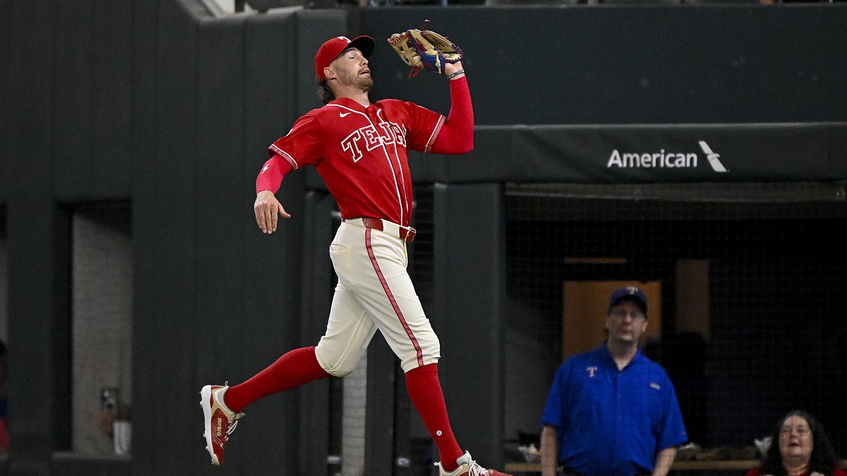 Texas Rangers right fielder Brandon Nimmo reaches up with his glove to catch a foul ball on the run.