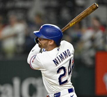 Texas Rangers right fielder Brandon Nimmo follows through on a swing with his bat raised over his shoulder.