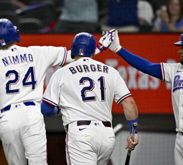Rangers teammates Brandon Nimmo, Jake Burger, and Elias Díaz celebrate after a run scores.