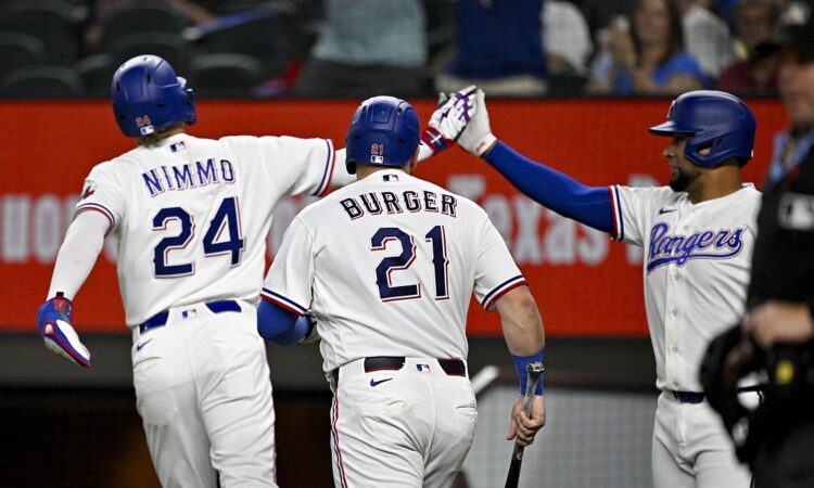 Rangers teammates Brandon Nimmo, Jake Burger, and Elias Díaz celebrate after a run scores.