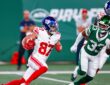 New York Giants wide receiver Braxton Berrios tucks the ball and cuts upfield as a New York Jets defender pursues.