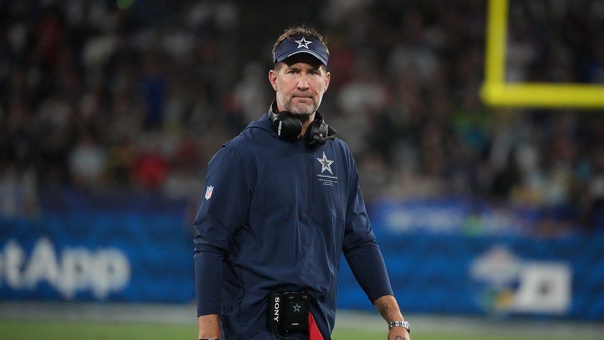 Dallas Cowboys head coach Brian Schottenheimer walks the sideline with a headset around his neck.