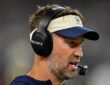 Cowboys head coach Brian Schottenheimer speaks into his headset microphone on the sideline during the game.