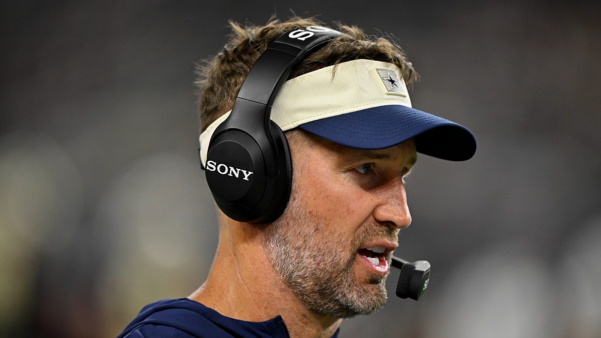 Cowboys head coach Brian Schottenheimer speaks into his headset microphone on the sideline during the game.