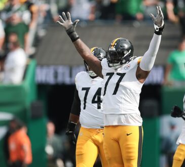 Pittsburgh Steelers offensive tackle Broderick Jones raises both arms in celebration as teammates walk past.