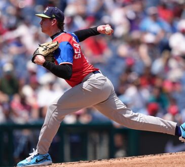 American League pitcher Caden Scarborough, No. 11, drives off the mound to deliver a pitch.
