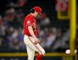 Texas Rangers pitcher Cal Quantrill looks down at his raised leg as he stands on the field in a red Tejas jersey.