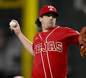 Texas Rangers pitcher Cal Quantrill, in a red Tejas jersey, rears back to throw a pitch.