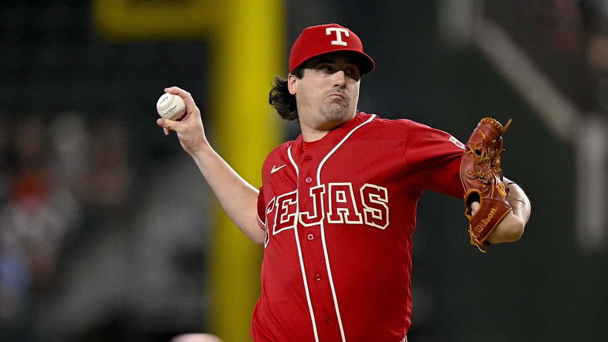 Texas Rangers pitcher Cal Quantrill, in a red Tejas jersey, rears back to throw a pitch.