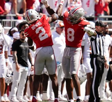 Ohio State Buckeyes safety Caleb Downs and linebacker Arvell Reese raise their arms in celebration near the Texas sideline.