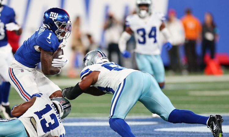 Two Dallas Cowboys defenders wrap up New York Giants wide receiver Malik Nabers after a catch.