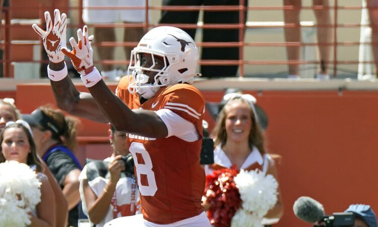 Texas Longhorns wide receiver Cam Coleman, No. 8, reaches up for a touchdown pass as the ball arrives.