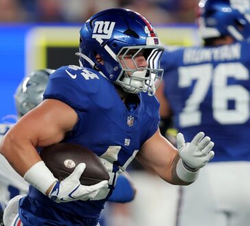 Giants running back Cam Skattebo tucks the ball and cuts upfield with a Cowboys defender trailing behind him.