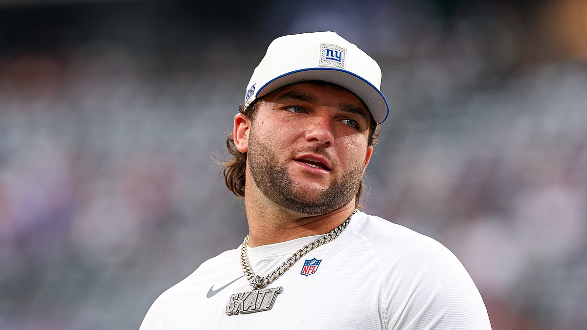 New York Giants running back Cam Skattebo looks toward the sideline in a Giants cap and warmup shirt.