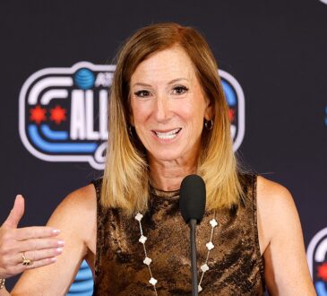 WNBA commissioner Cathy Engelbert speaks at a microphone in front of an All-Star backdrop.