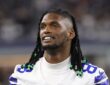 Dallas Cowboys wide receiver CeeDee Lamb smiles as he looks on from the sideline without his helmet.
