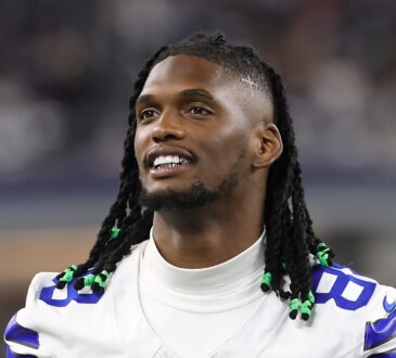 Dallas Cowboys wide receiver CeeDee Lamb smiles as he looks on from the sideline without his helmet.