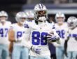 Dallas Cowboys wide receiver CeeDee Lamb holds a football during warmups with teammates behind him.