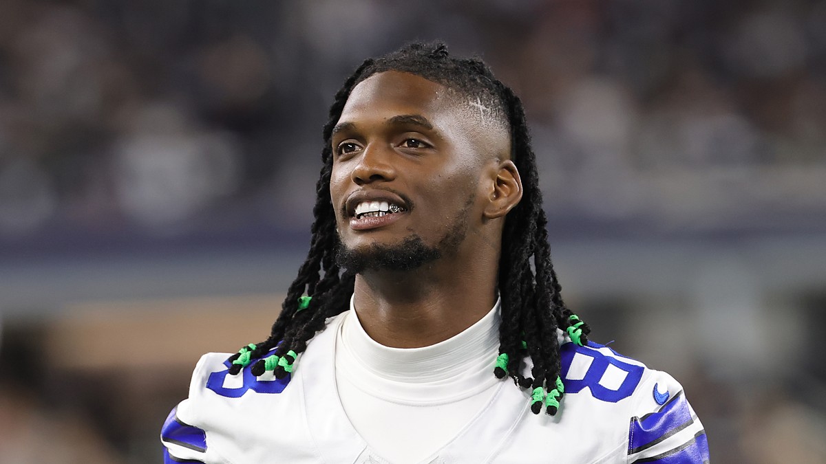 Dallas Cowboys wide receiver CeeDee Lamb smiles as he looks on from the sideline without his helmet.