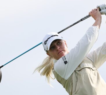 Golfer Charley Hull follows through on her tee shot, her club extended behind her against a gray sky.