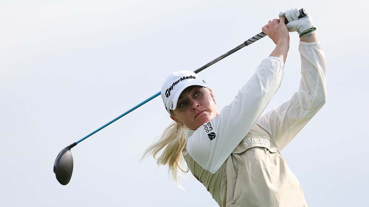 Golfer Charley Hull follows through on her tee shot, her club extended behind her against a gray sky.