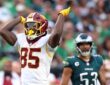 Washington Commanders tight end Chig Okonkwo signals first down with one arm raised during a game against the Eagles.