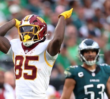 Washington Commanders tight end Chig Okonkwo signals first down with one arm raised during a game against the Eagles.