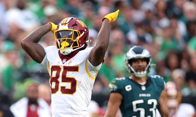 Washington Commanders tight end Chig Okonkwo signals first down with one arm raised during a game against the Eagles.