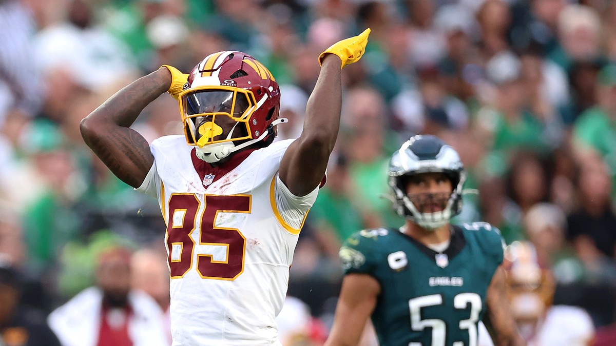 Washington Commanders tight end Chig Okonkwo signals first down with one arm raised during a game against the Eagles.