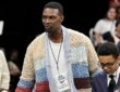 NBA Hall of Famer Chris Bosh, in a patchwork cable-knit cardigan and VIP credential, walks through the courtside crowd.