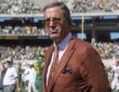Texas athletics director Chris Del Conte stands on the field in a burnt orange jacket after a game.