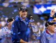 Rangers executive Chris Young smiles and holds the Commissioner's Trophy as blue confetti falls around him.