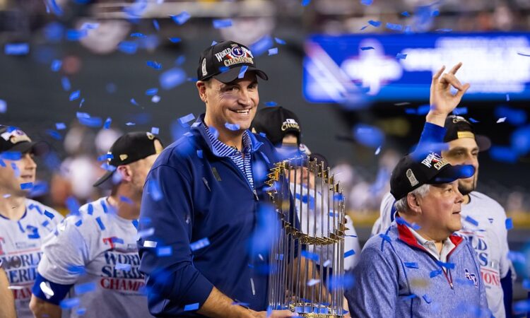Rangers executive Chris Young smiles and holds the Commissioner's Trophy as blue confetti falls around him.