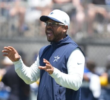 Cowboys defensive coordinator Christian Parker gestures with both hands as he calls out instructions at practice.